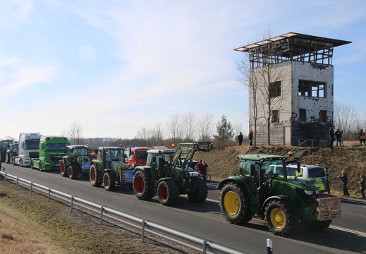 LKWs und Traktoren passieren den ehemaligen Grenzturm